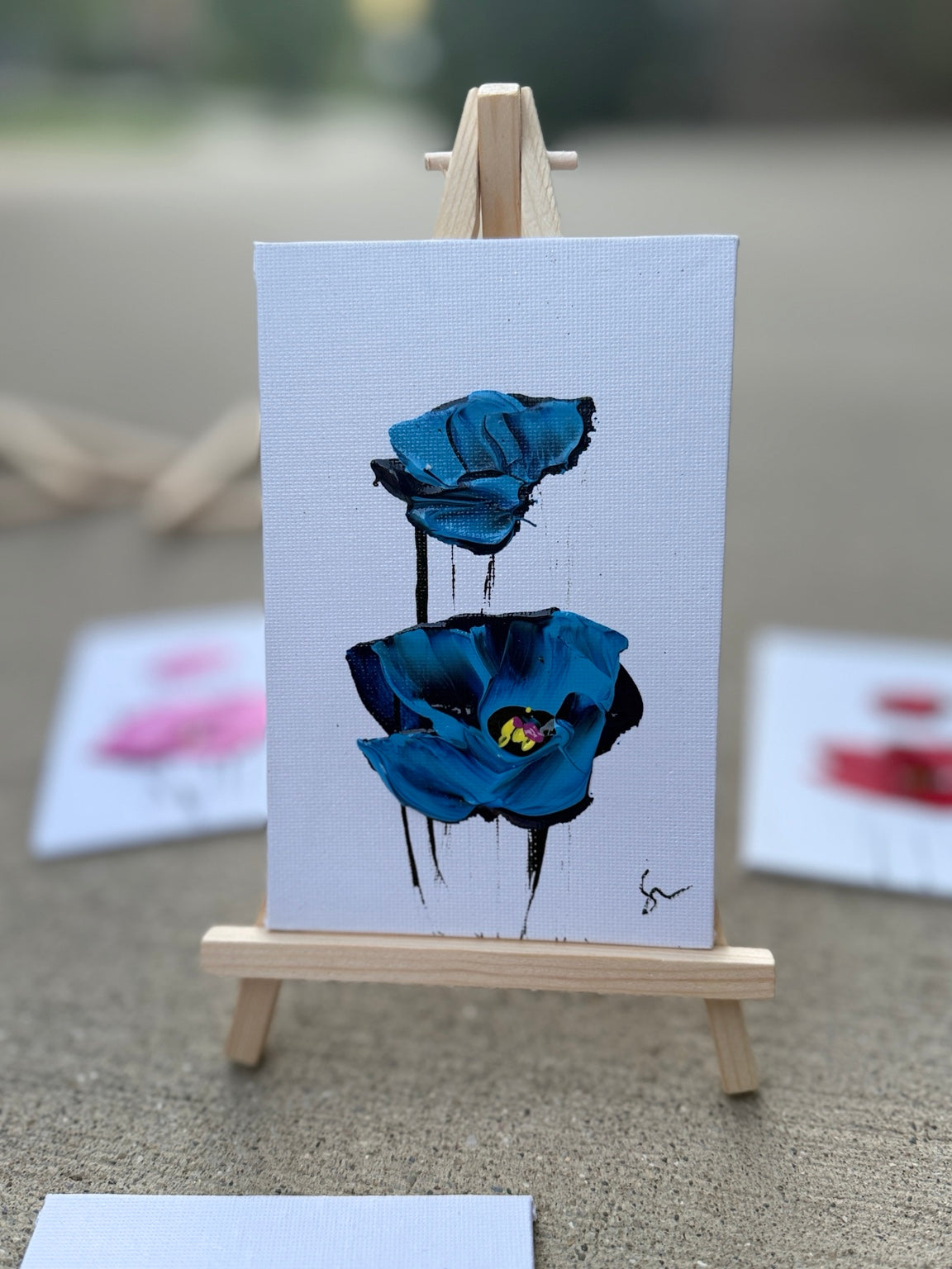 Blue Sam Glenn poppy painting on a 4x6 canvas board with a wooden easel